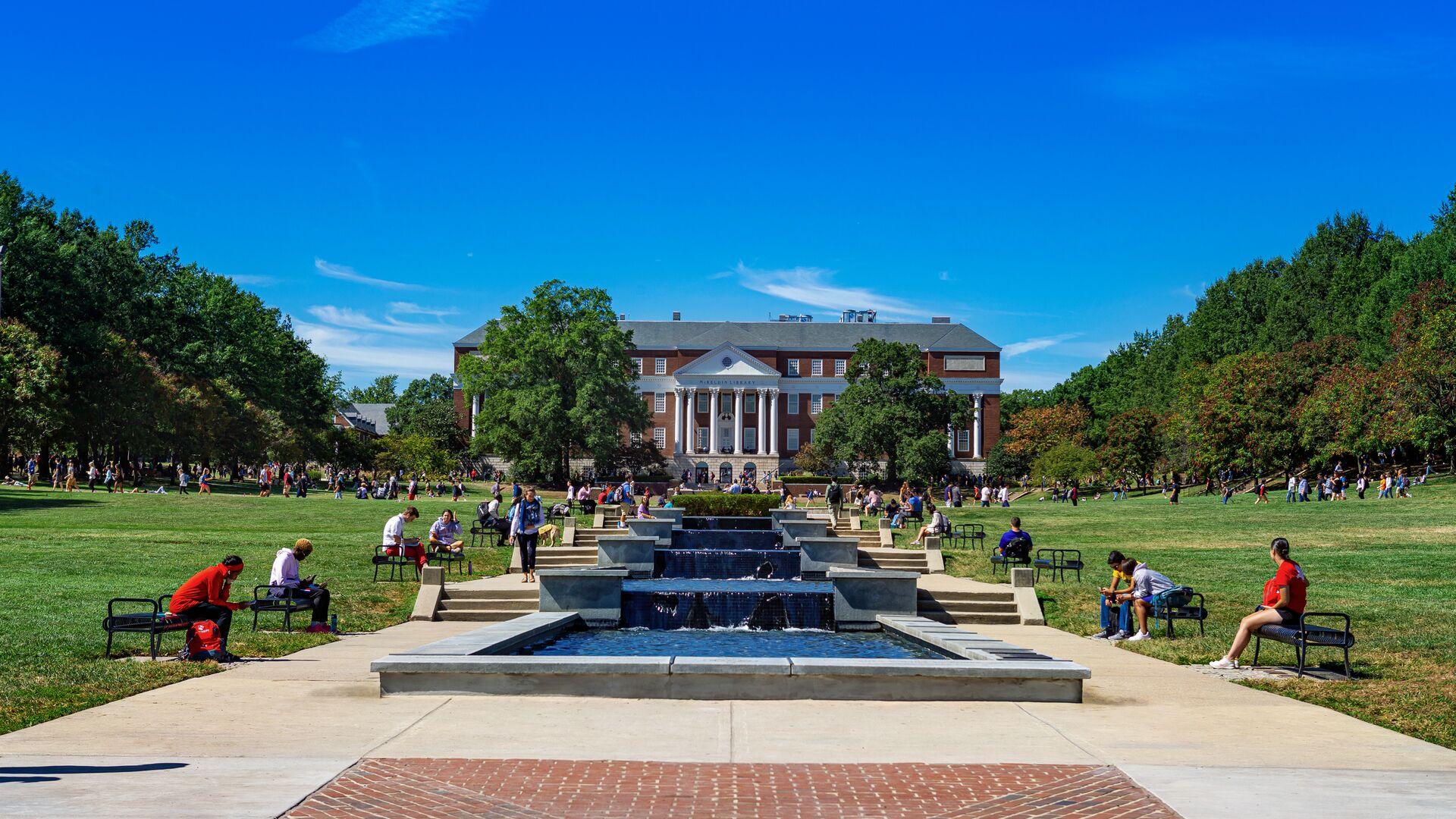 Warm bright day at the end of ODK fountain looking up towards McKeldin Library, Students sit and benches and on the grass studying and enjoying the day