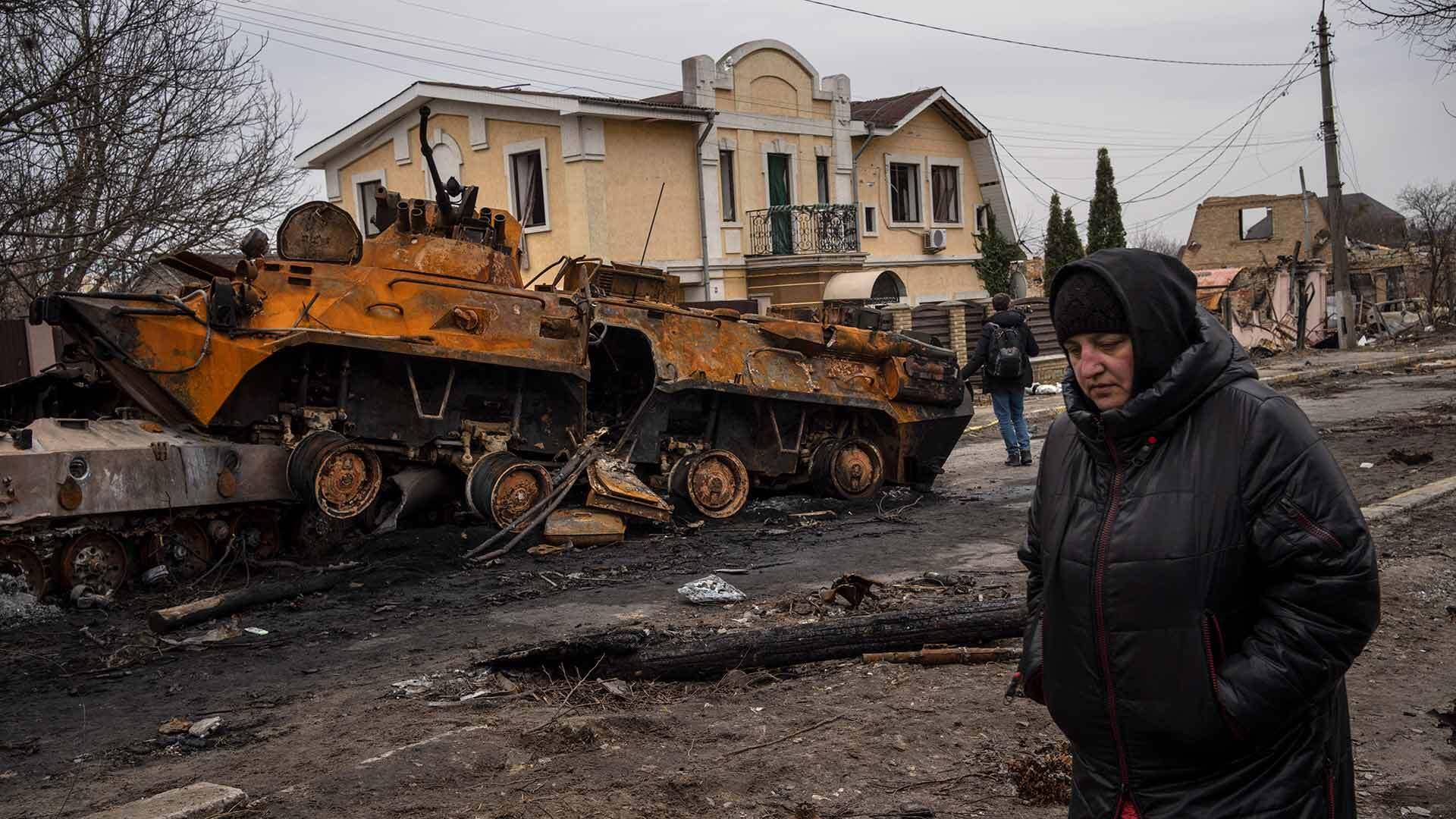 A woman walks next to a destroyed Russian armor vehicle in Bucha, a Kyiv suburb that was the site of a massacre of Ukrainian civilians