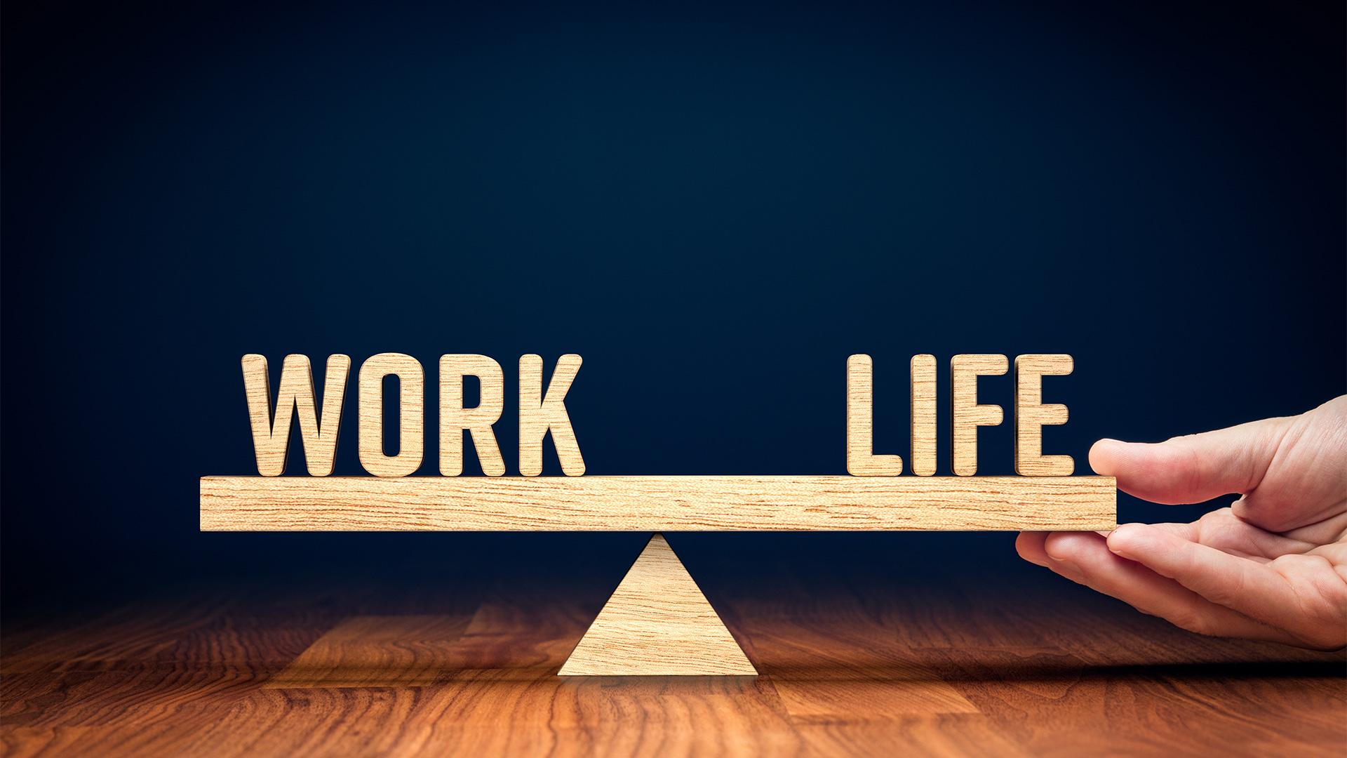 A wooden scale holds the words "work" and "life" on either side